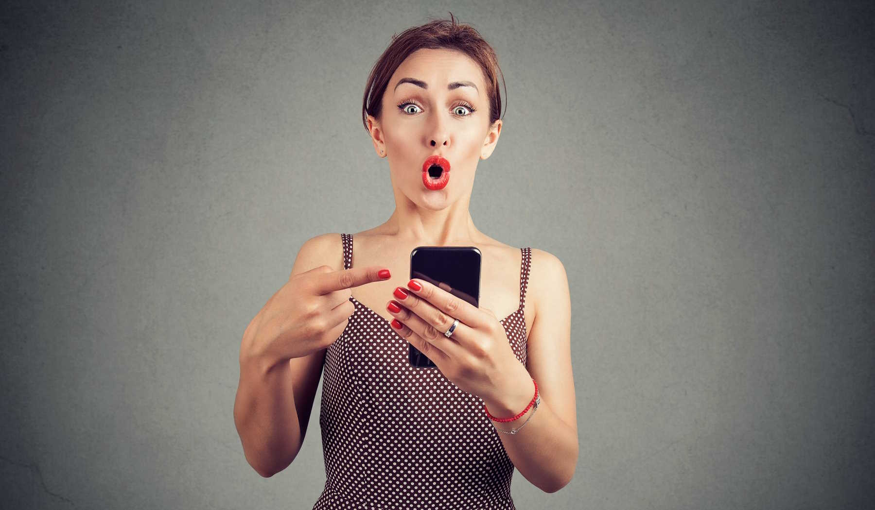 nő telefonját mutat valamit és látványosan meglepődik