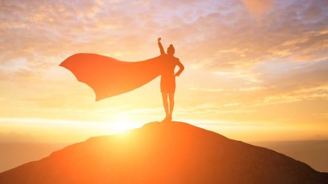 nő áll a dombon palásttal szuperhősként