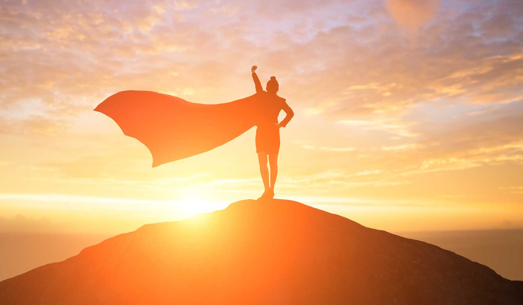 nő áll a dombon palásttal szuperhősként