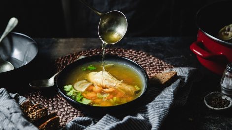 aranyló csirkehúslevest szed tányérba egy nő