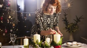 szép fiatal lány karácsonyi asztalt dekorál vacsorához