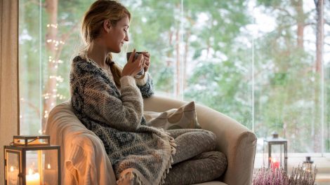 nő kávéval a kezében ül a fotelben