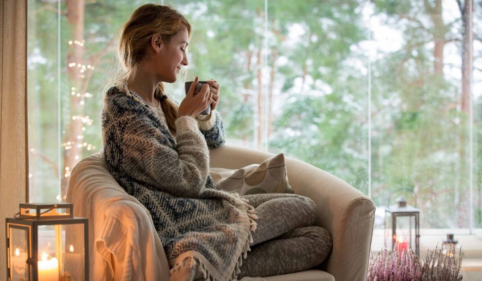 nő kávéval a kezében ül a fotelben