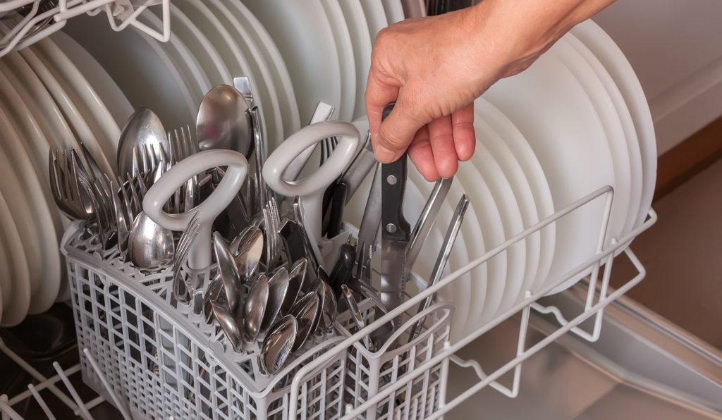kést rak a mosogatógépbe egy férfi