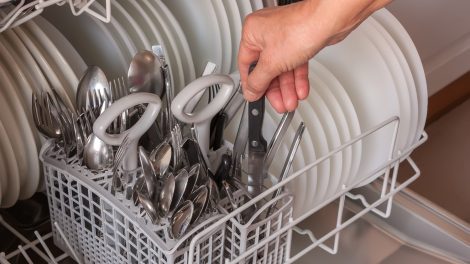 kést rak a mosogatógépbe egy férfi