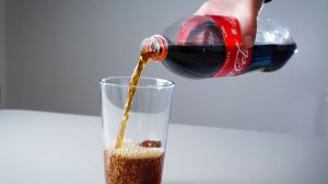 kólát tölt pohárba egy férfi