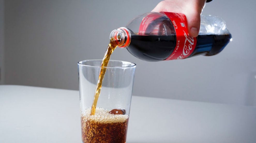 kólát tölt pohárba egy férfi