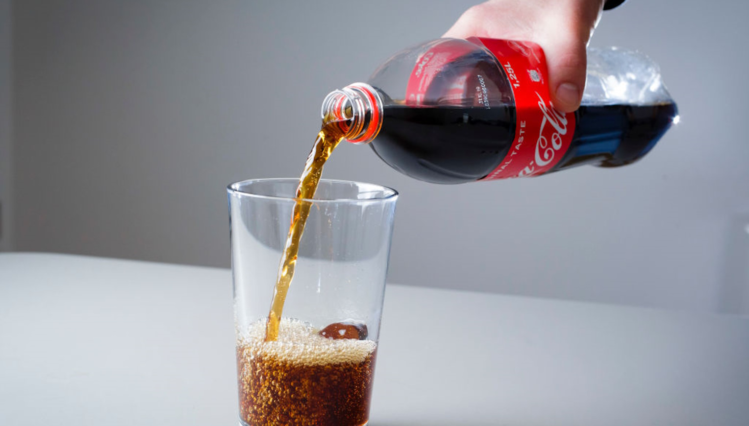 kólát tölt pohárba egy férfi