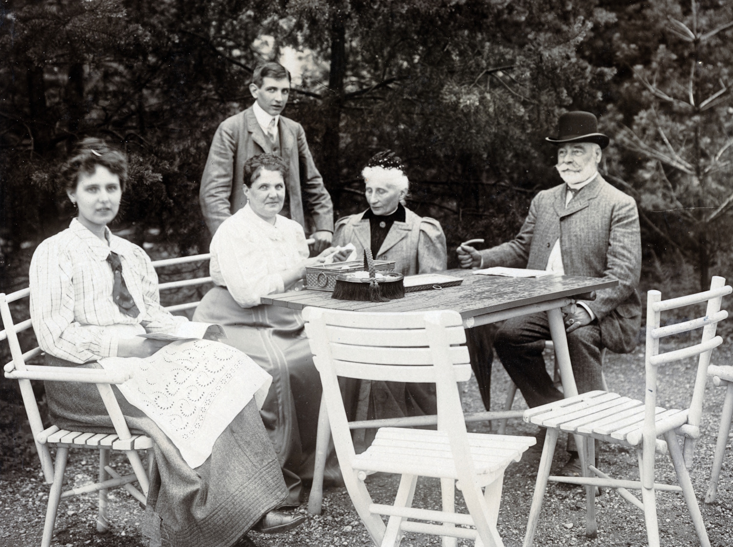 Hölgyek és urak beszélgetnek egy kerti asztalnál