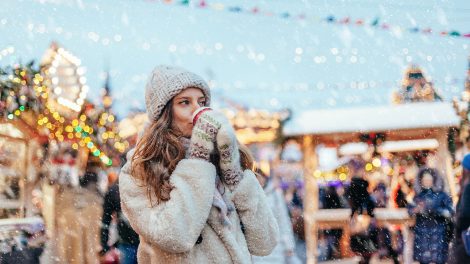 Lány forró italt iszik a karácsonyi vásáron