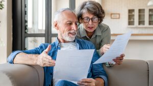 Idős házaspár szerződést olvas otthon a kanapén