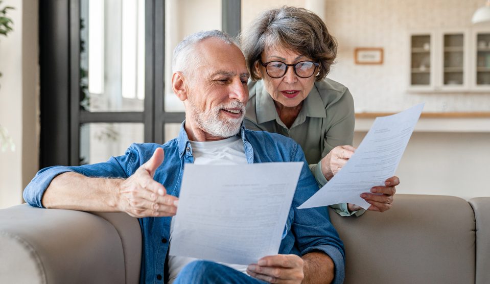 Idős házaspár szerződést olvas otthon a kanapén
