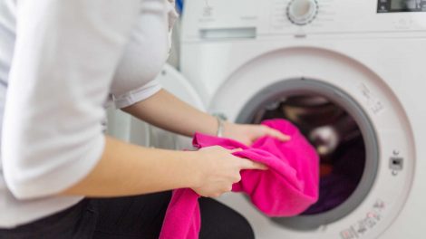 nő rózsaszín ruhát tesz a mosógépbe