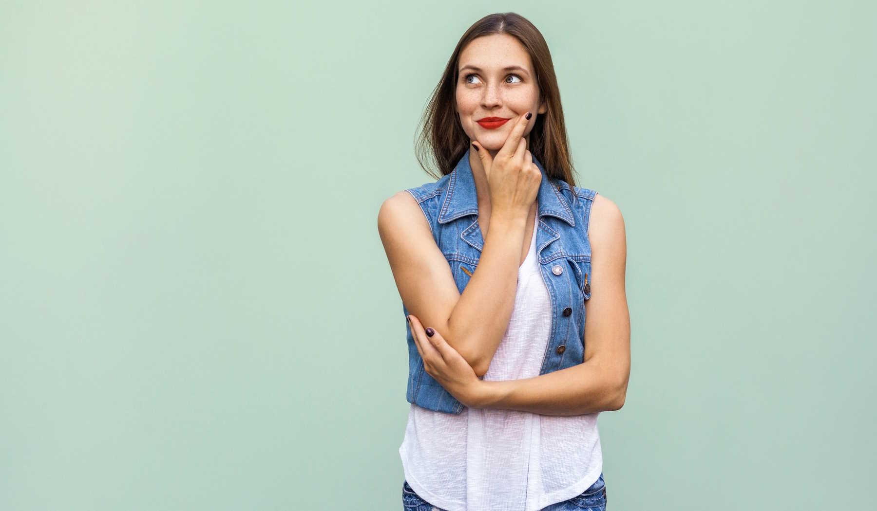 nő piros rúzzsal pózol a fal előtt