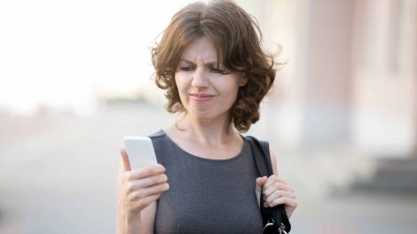 Nő stresszelve néz a mobiljára