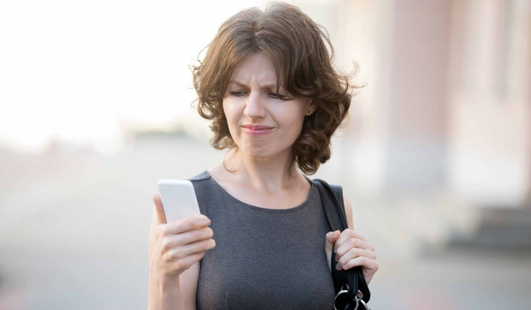 Nő stresszelve néz a mobiljára