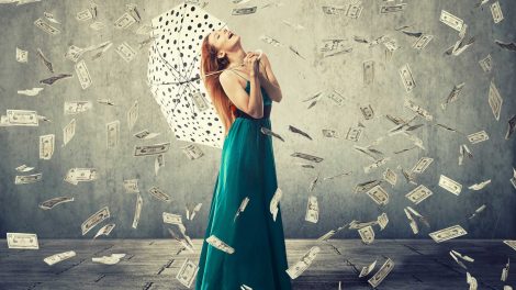 nő esernyővel áll a pénzeső alatt