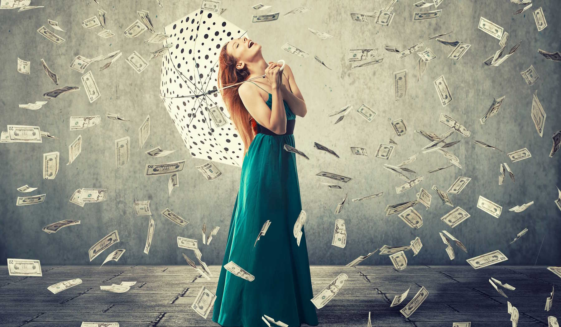 nő esernyővel áll a pénzeső alatt