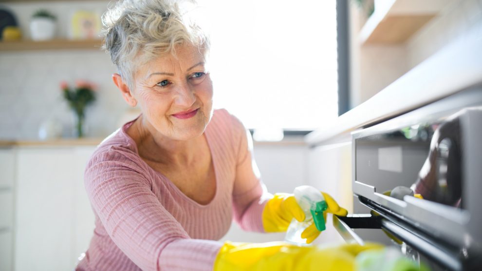 boldog középkorú nő sütőt takarít szódabikarbónával