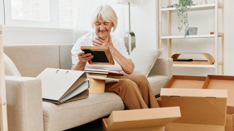 idős nő otthon ül a kanapén dobozokkal