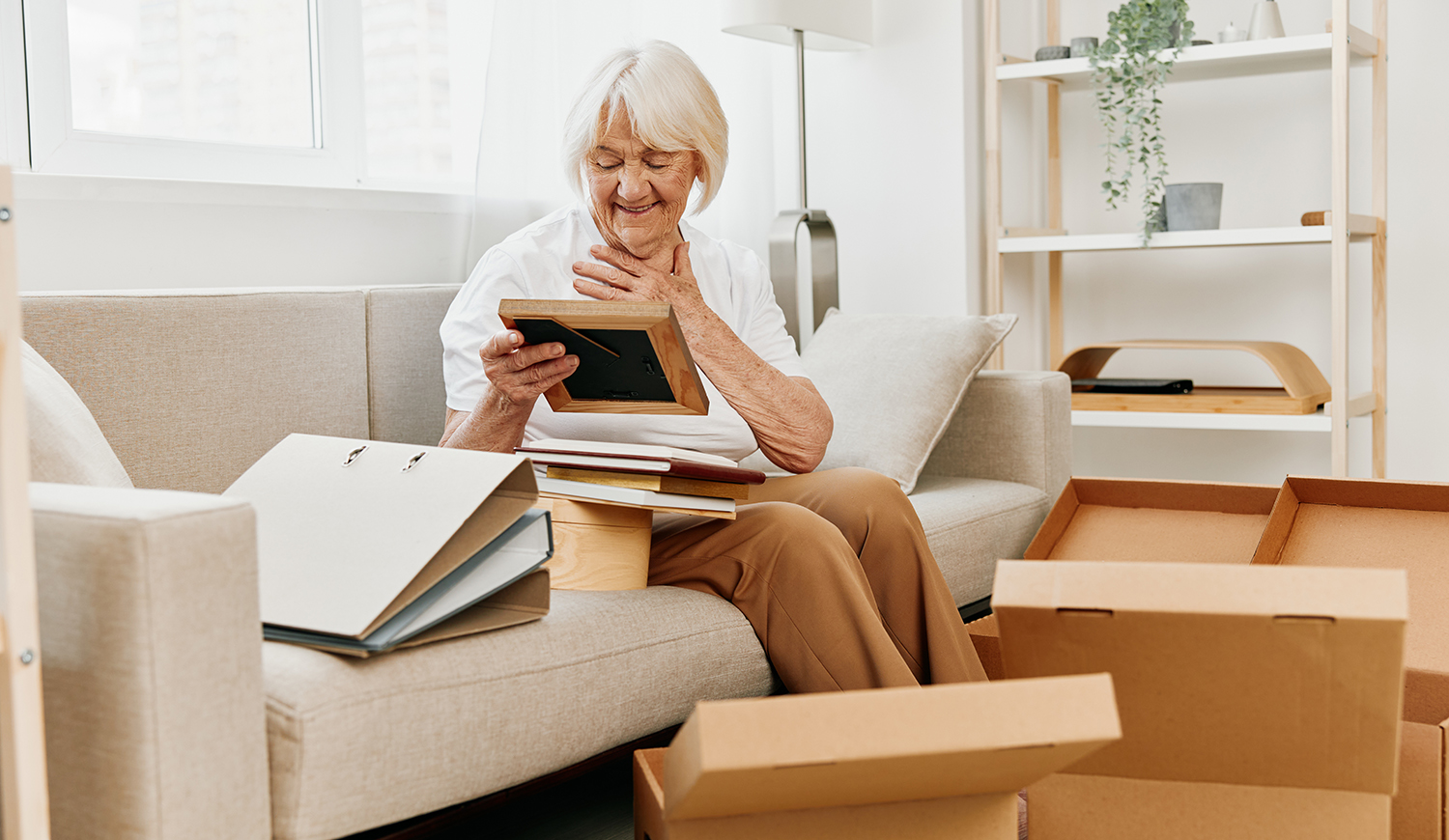 idős nő otthon ül a kanapén dobozokkal