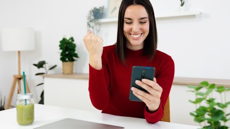 Egy lány mosolyogva nézi a telefonját