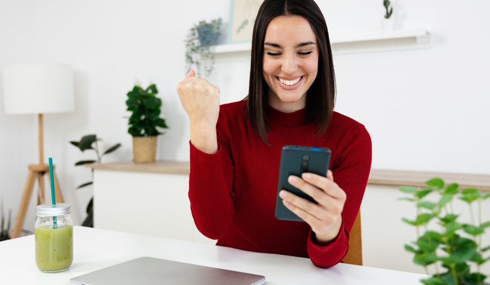 Egy lány mosolyogva nézi a telefonját