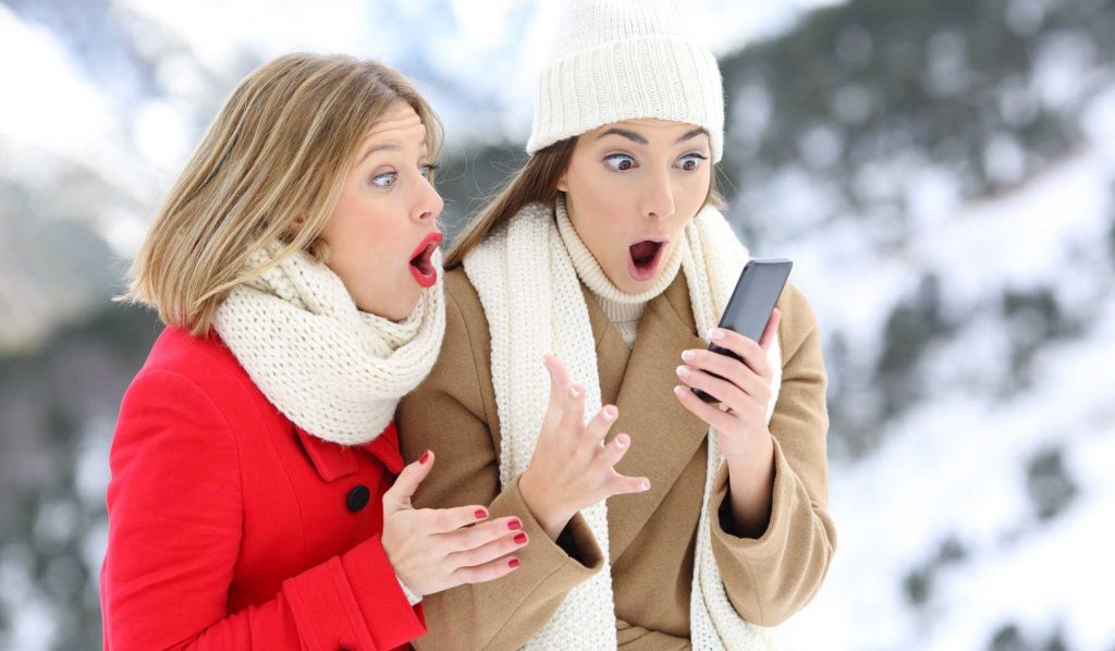 két nő télen a telefont nézi és meglepődnek valamin