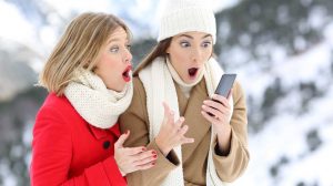 két nő télen a telefont nézi és meglepődnek valamin