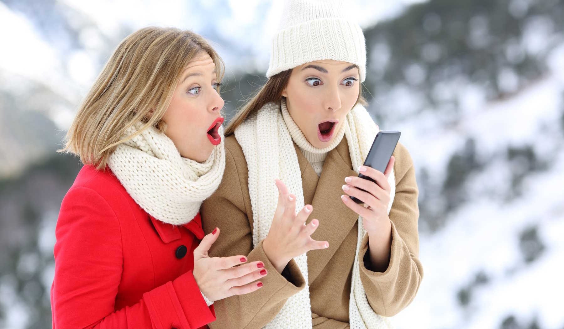 két nő télen a telefont nézi és meglepődnek valamin