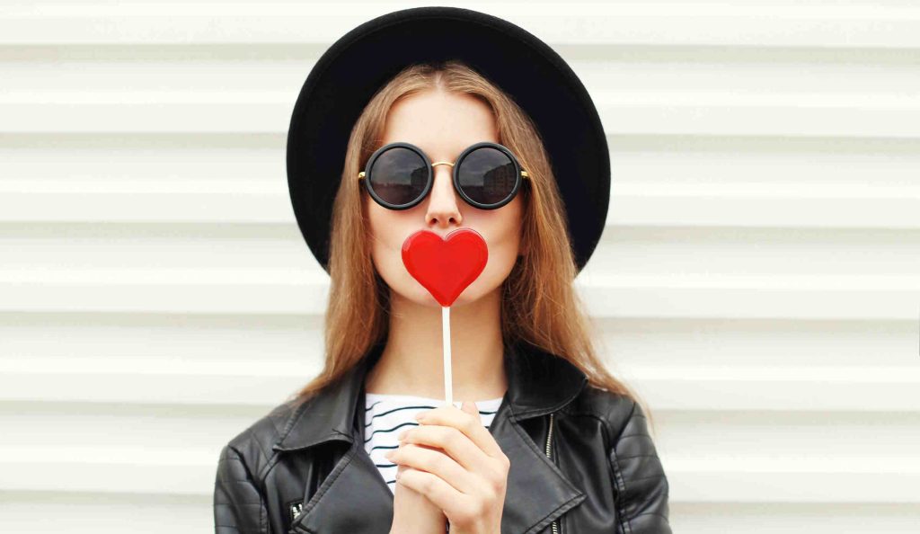 nő napszemüvegben szív alakú nyalókával