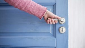 nő nyitja az ajtót fogja a kilincset