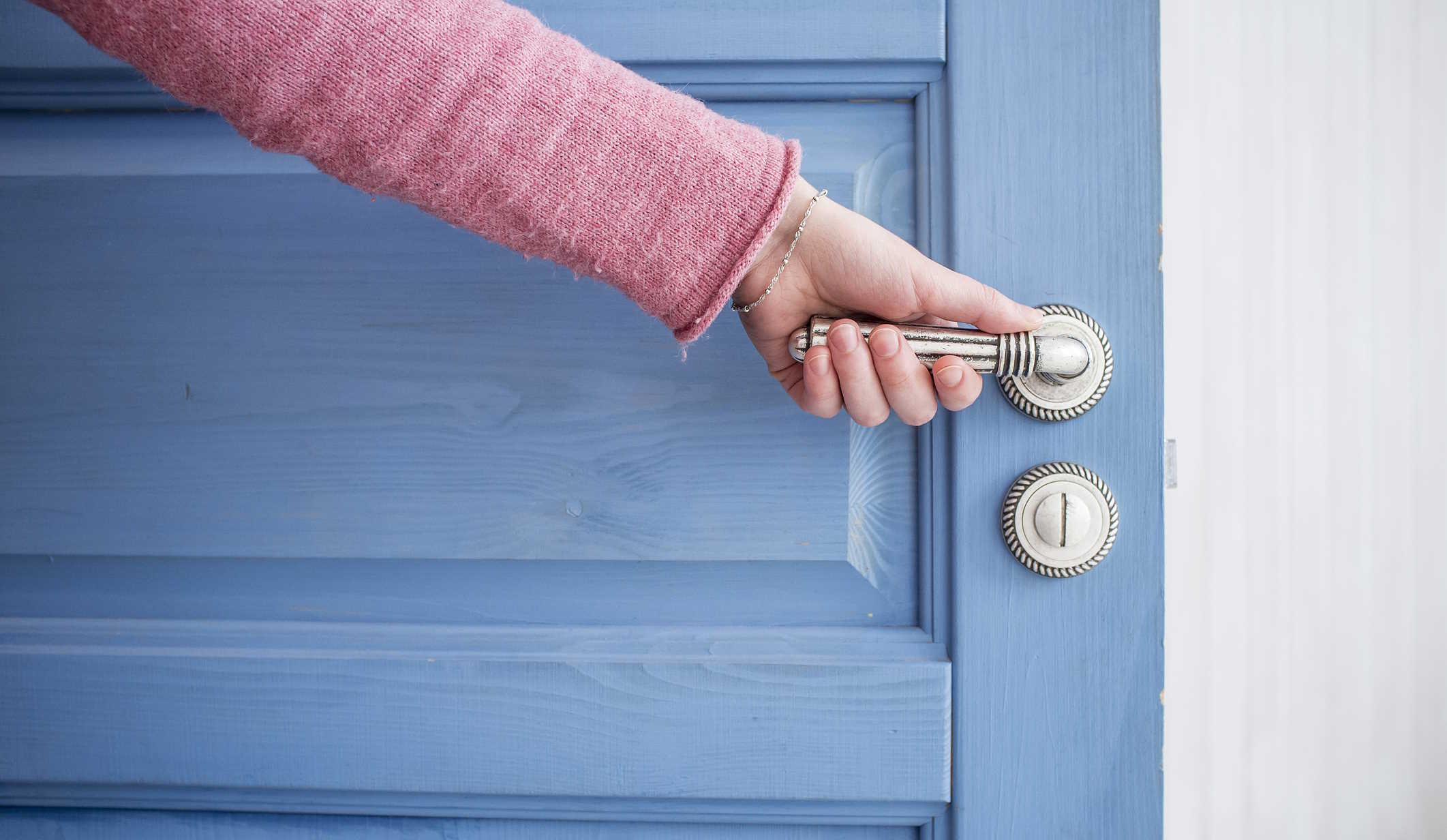 nő nyitja az ajtót fogja a kilincset