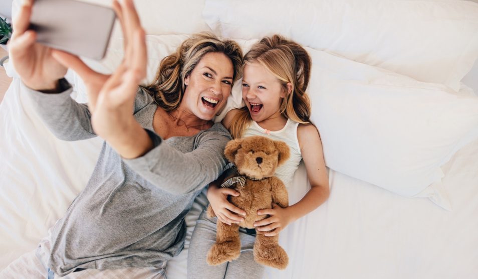 anya és lánya az ágyban boldogan szelfizik