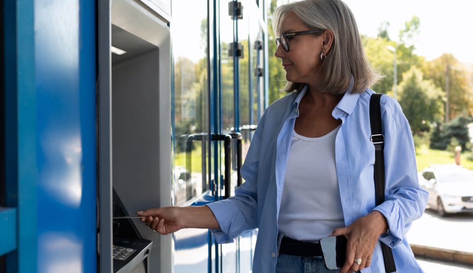 atm bankautomatából pénzt vesz fel egy idősebb nő