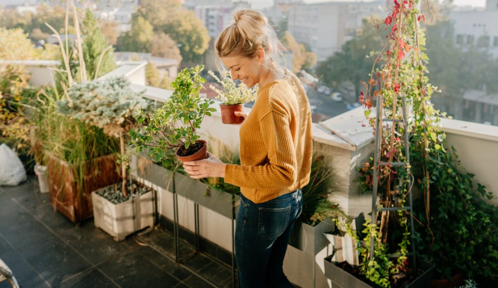nő az erkélyen kertészkedik és nagyon örül
