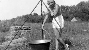 Egy lány főz a szabadban bográcsban