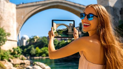 Mostar városának legendás hídja előtte turista nő fotózza