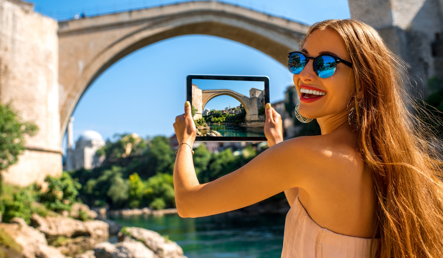 Mostar városának legendás hídja előtte turista nő fotózza