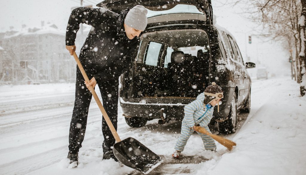 apa és kisfia havat lapárolnak a kocsi körül