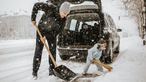 apa és kisfia havat lapárolnak a kocsi körül
