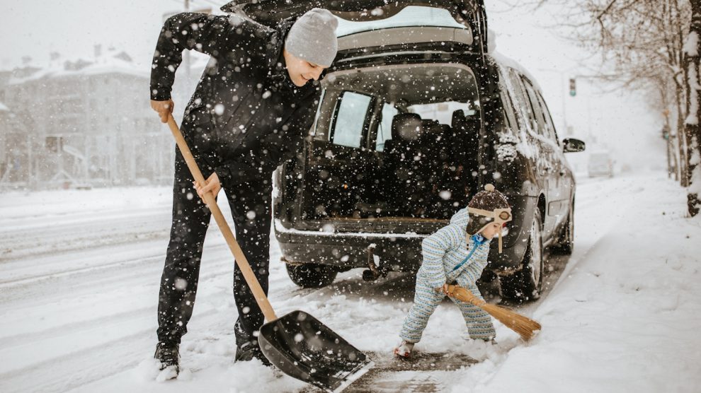apa és kisfia havat lapárolnak a kocsi körül