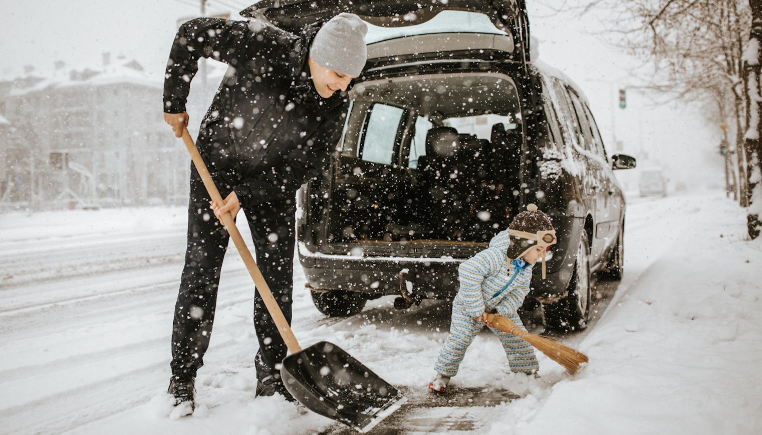 apa és kisfia havat lapárolnak a kocsi körül