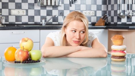 nő döntés előtt, fánkok, gyümölcsök között