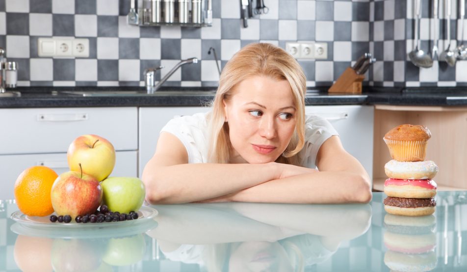 nő döntés előtt, fánkok, gyümölcsök között