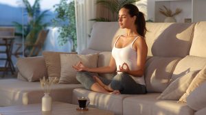 Fiatal nő jógázik és meditál a kanapén