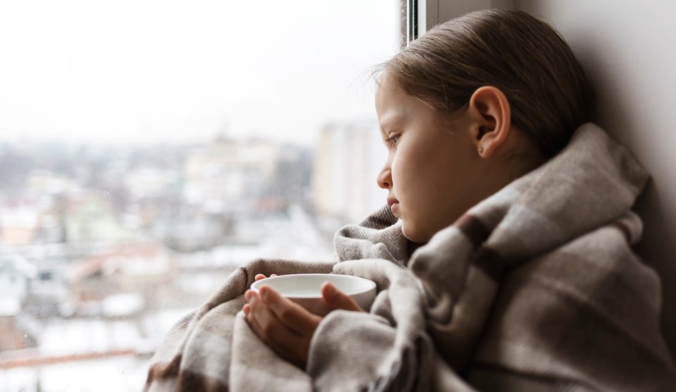 Szomorú kislány az ablakban ül teával a kezében