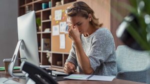 nő ül az asztalnál és fáj a feje