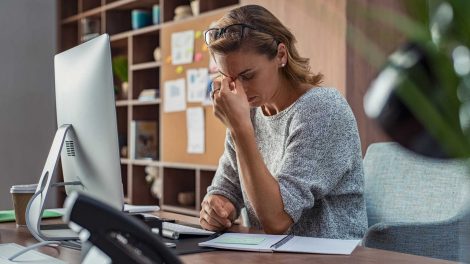 nő ül az asztalnál és fáj a feje