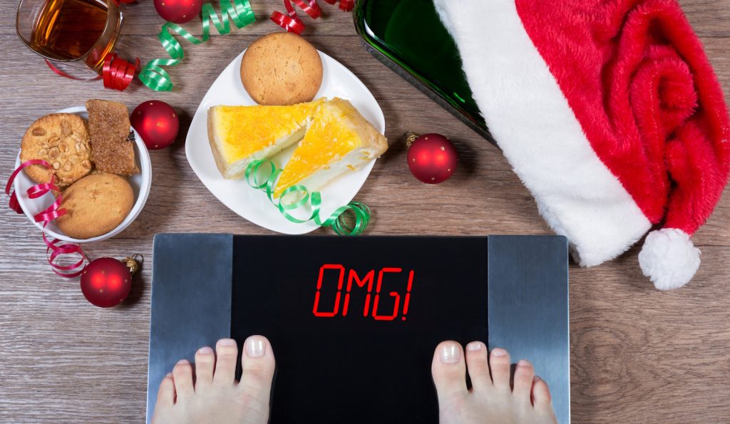 mérlegen álló ember, sütivel, karácsonyi desszertekkel